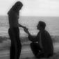 romantic marriage proposal on the beach with man kneeling before his girlfriend
