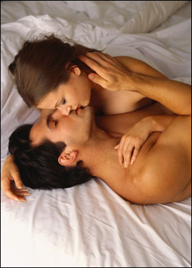 sexy dark haired couple having sex in their bed while kissing