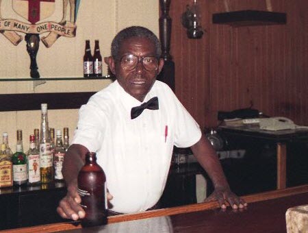 friendly barman jamaican bartender handing a bottle of beer to drink