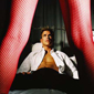 sexy man on bed with shirt ripped open eyeing prostitute with long sexy legs in fishnet stockings